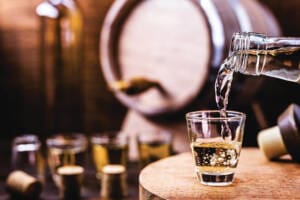 Glass of golden rum, with bottle. Bottle pouring alcohol into a small glass. Brazilian export type drink. Brazilian product for export, distilled drink known as brandy or pinga. Day of cachaça.