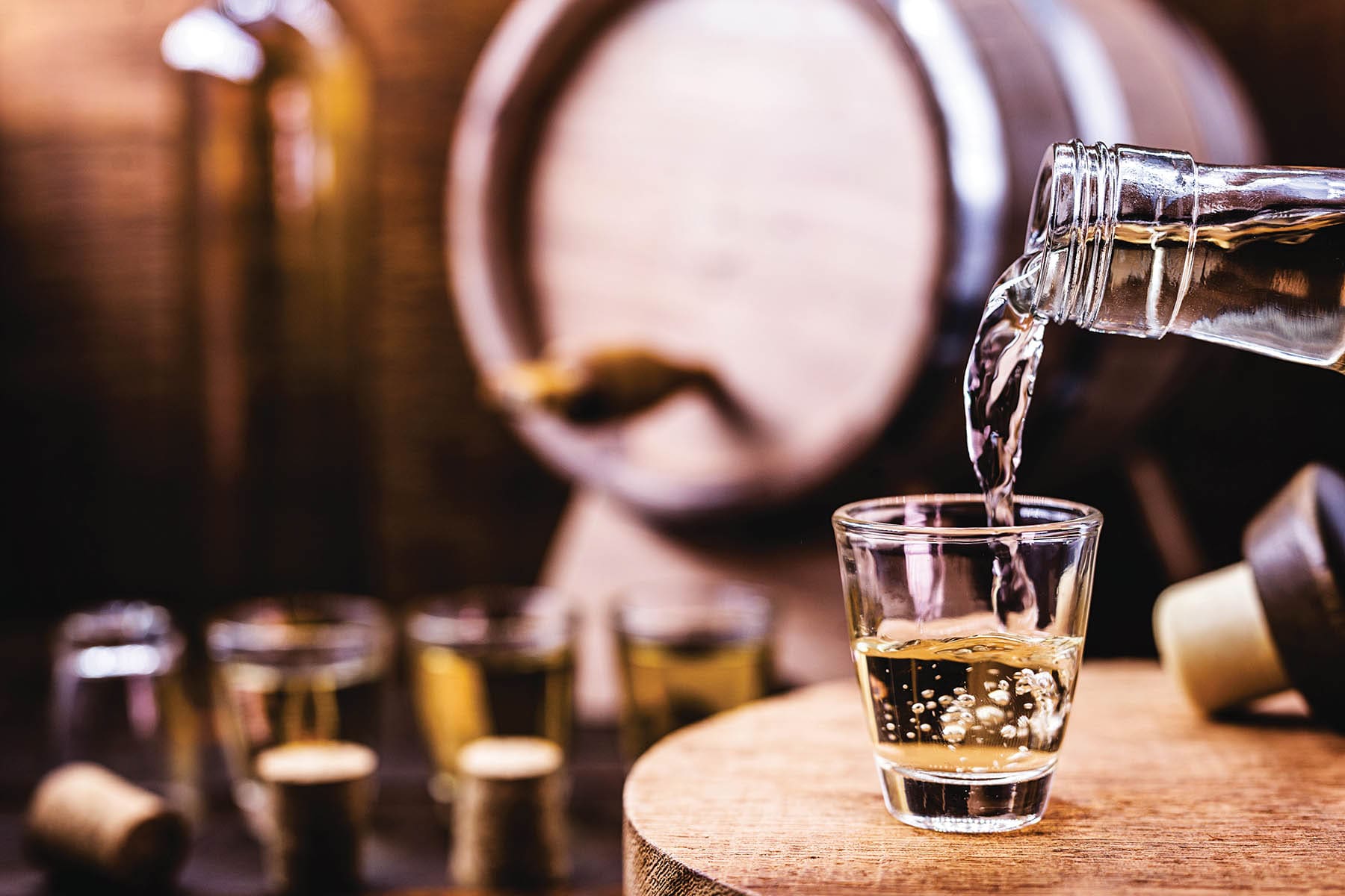 Glass of golden rum, with bottle. Bottle pouring alcohol into a small glass. Brazilian export type drink. Brazilian product for export, distilled drink known as brandy or pinga. Day of cachaça.