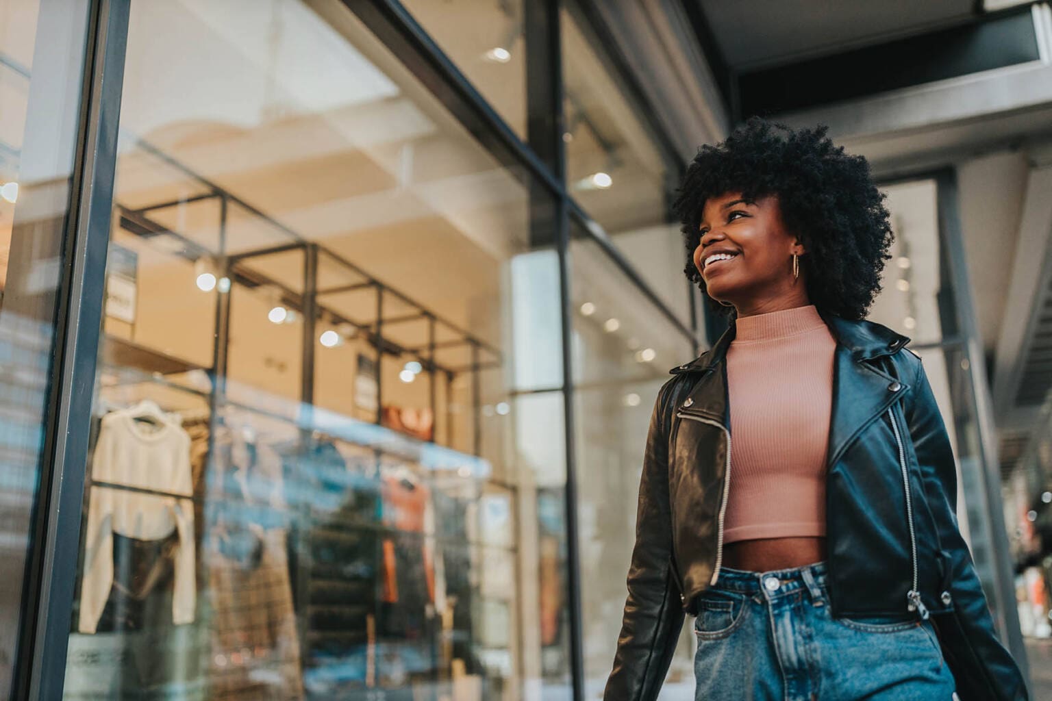 A young woman out shopping in the city. Afro female standing in front of boutique and looking in the shop window